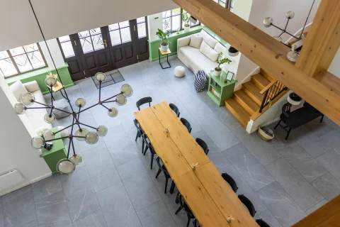 Nappali felülről nézve, hosszú fa étkezőasztallal, fekete székekkel és zöld szekrényekkel